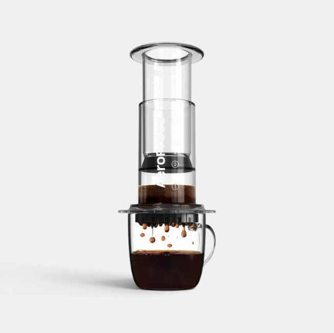 Bootlegger Coffee AeroPress Go portable coffee maker brewing fresh coffee into a clear glass mug