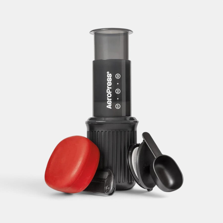 Bootlegger Coffee AeroPress Go portable coffee maker with black plunger, filter cap, red lid, and black coffee scoop.