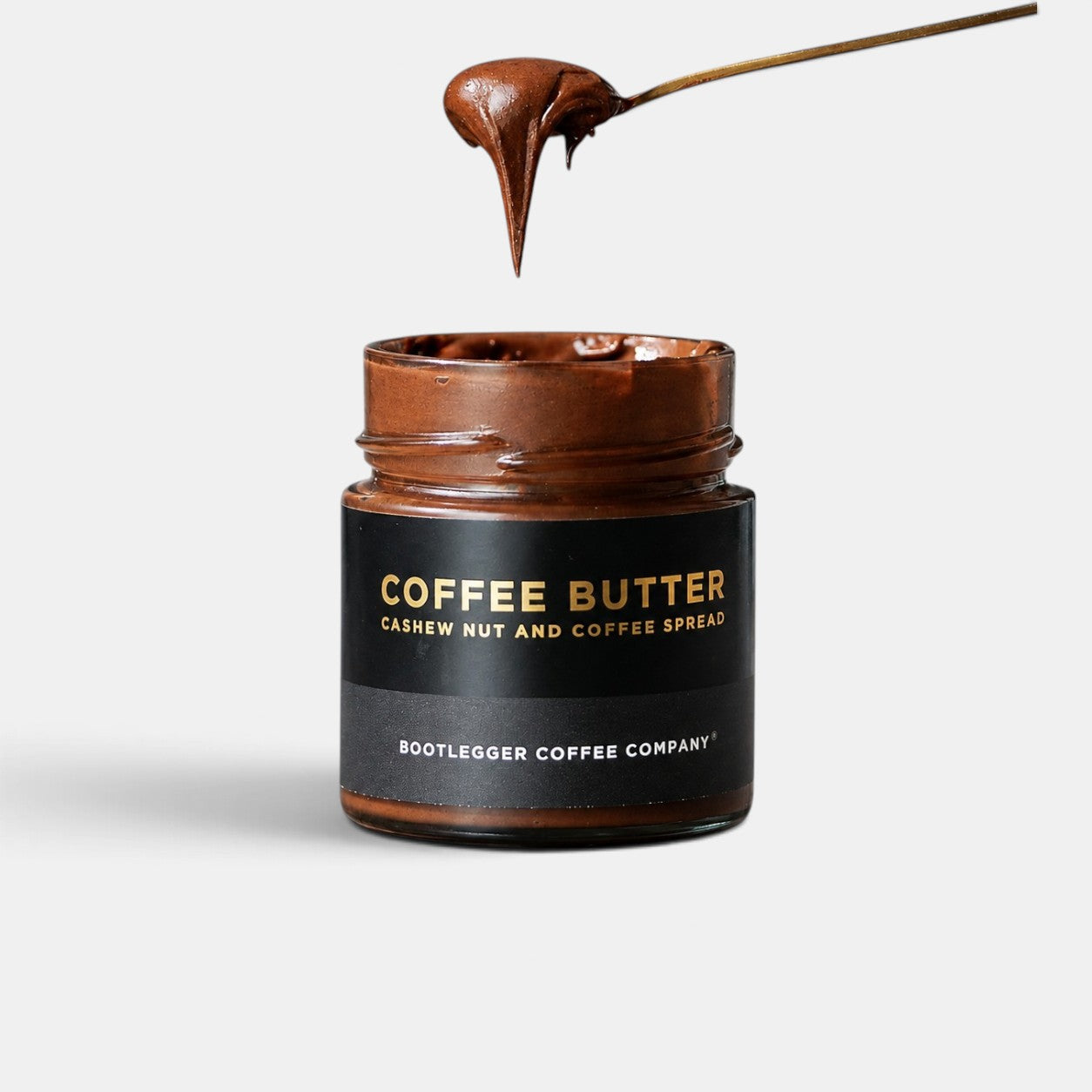 Bootlegger Coffee jar of creamy brown cashew nut and coffee butter spread with a spoonful being lifted