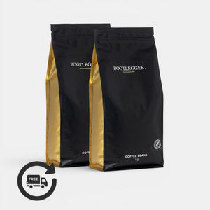 Two 1kg bags of Bootlegger Coffee Colombia Decaf coffee beans in black and gold packaging with a subscription icon.