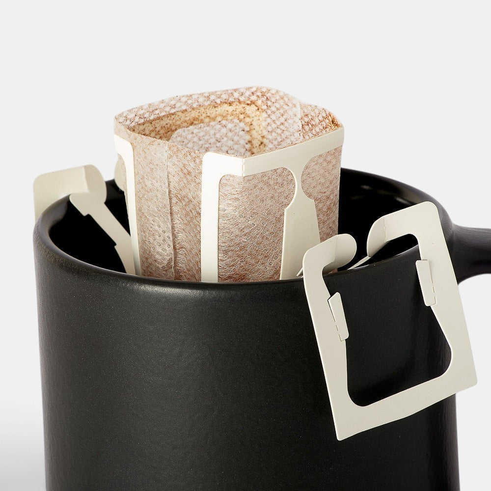 Bootlegger Coffee drip bag perched on a matte black ceramic mug for easy single-serve brewing