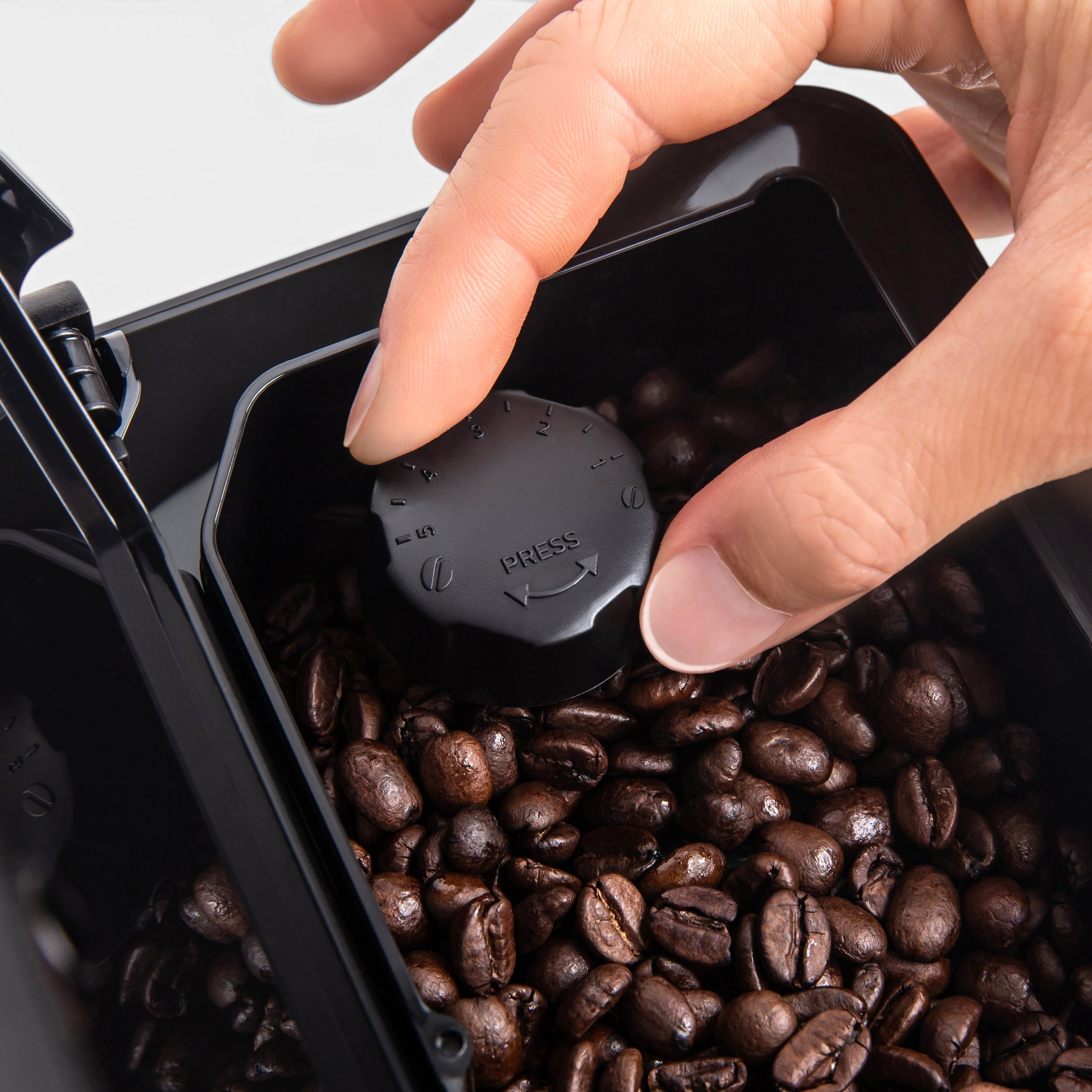 Bootlegger Coffee Gaggia Magenta Plus bean hopper with a hand adjusting the black circular grind setting dial