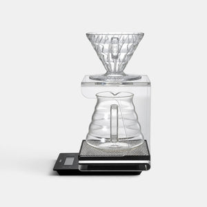 Bootlegger Coffee Hario V60 acrylic drip station with a clear glass dripper and carafe on a black digital scale.