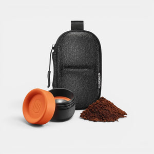 Bootlegger Coffee Wacaco Minipresso GR2 espresso maker parts with orange cap, filter basket, and coffee grounds in case