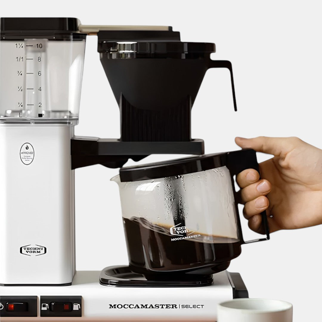 Bootlegger Coffee MoccaMaster Select filter coffee machine in white with a glass carafe being held by a hand