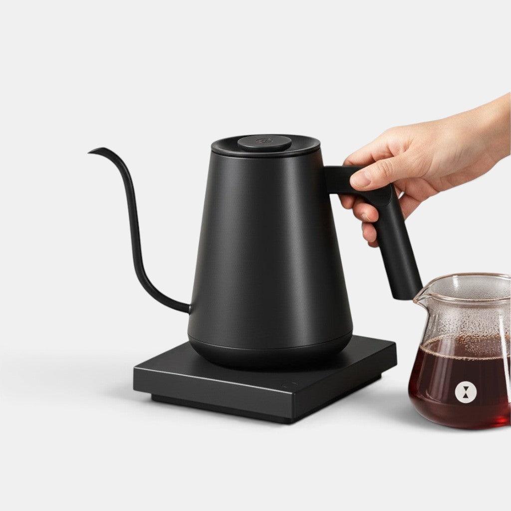 Bootlegger Coffee Timemore Fish Pro matte black electric gooseneck kettle on a base with a hand holding the handle